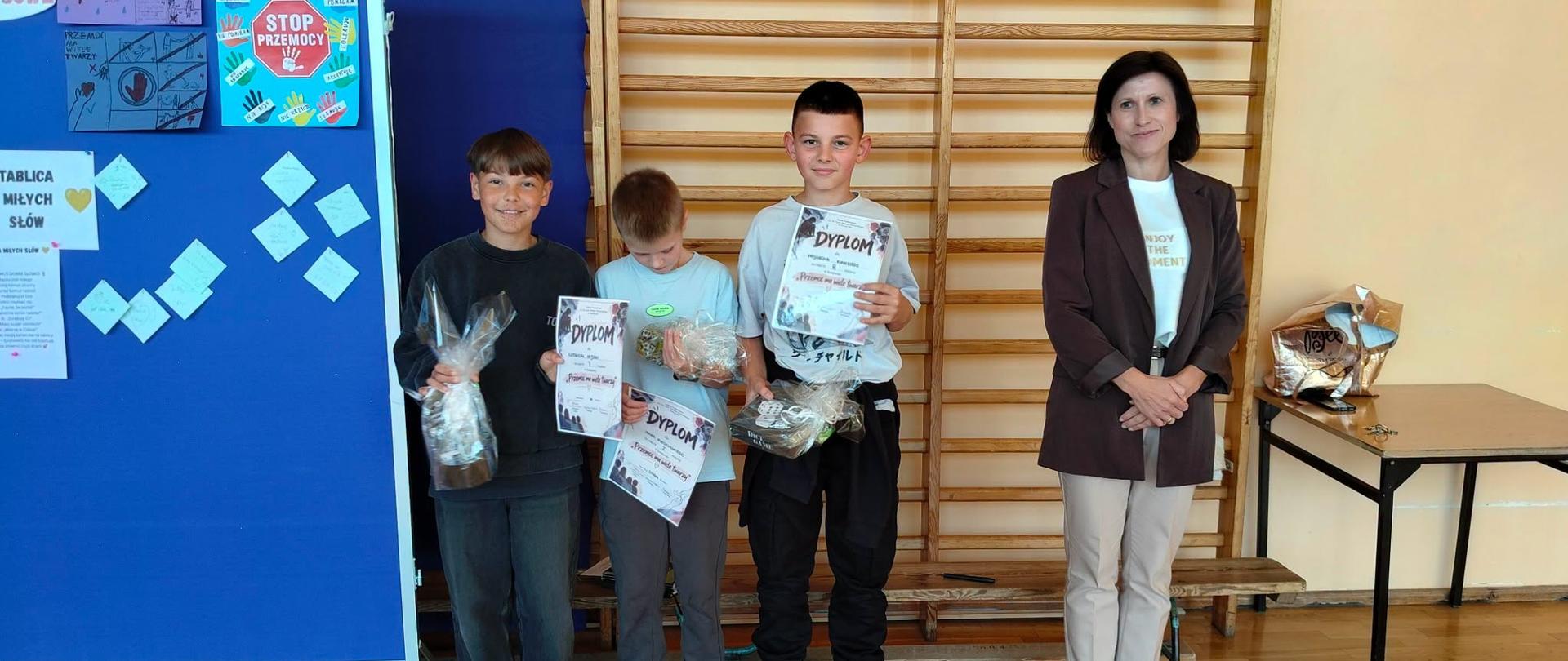 Trzech zwycięskich uczniów w konkursie na najlepszy plakat przeciw przemocy wraz z panią wicedyrektor