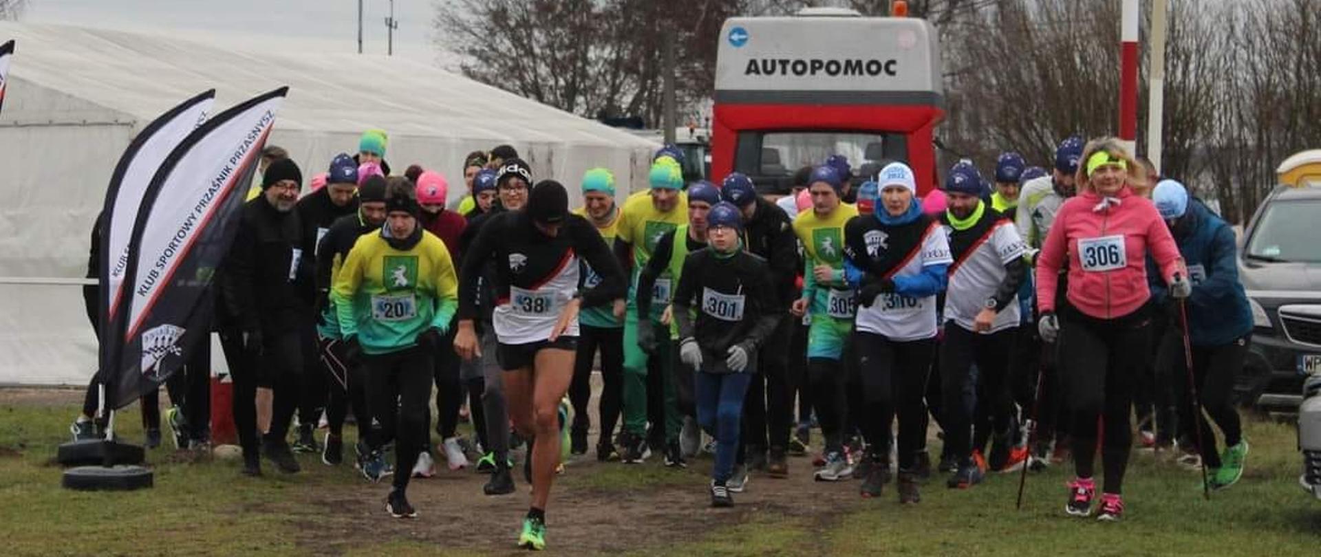 Zdjęcie przedstawia biegnących zawodników zaraz po wystartowaniu wyścigu.