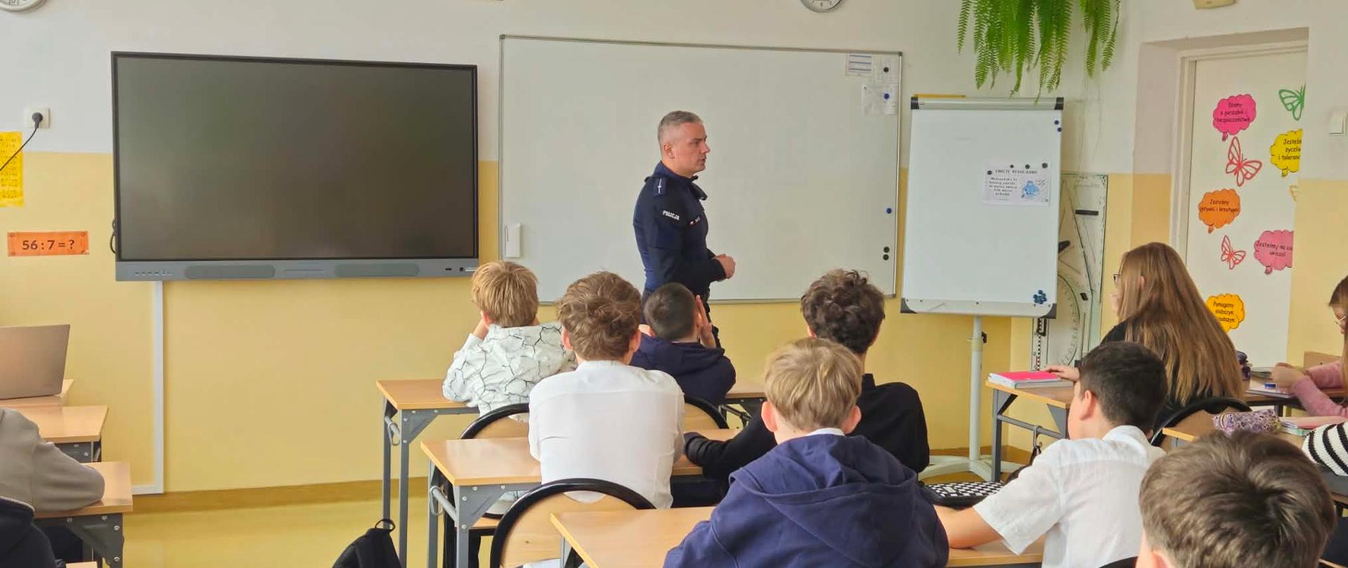 Na zdjęciu uczniowie oraz pan policjant prowadzący pogadankę. 
