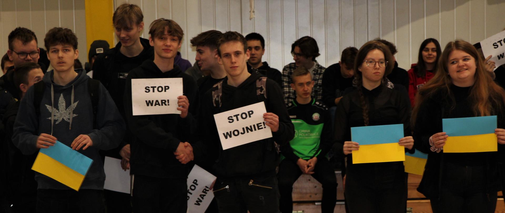 Uczniowie Zespołu Szkół w Chocianowie podczas manifestacji trzymają flagi Ukrainy i kartki z napisem "Stop Wojnie"