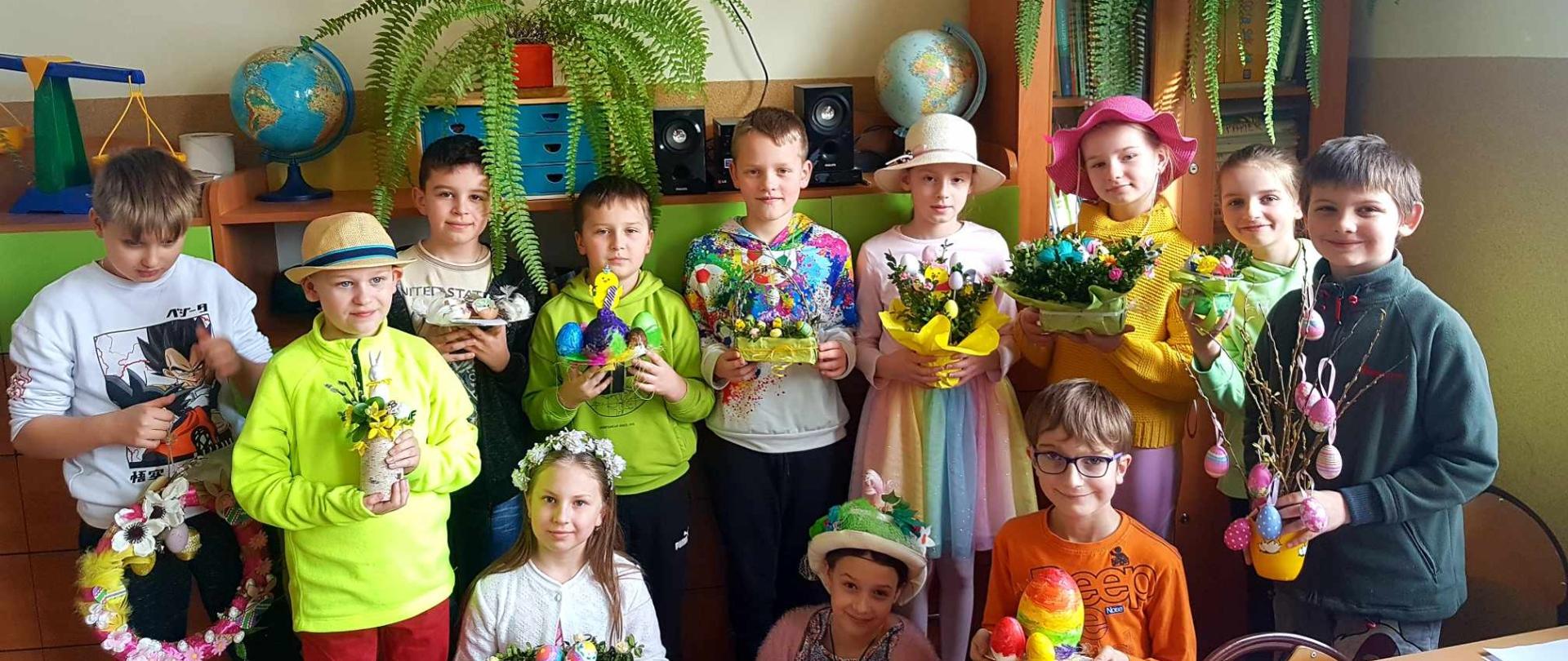 Dzieci w wiosennych barwach z wytworami wielkanocnych warsztatów.