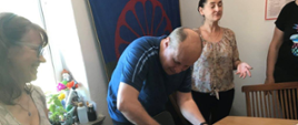 Uczestnicy warsztatów przy stole przygotowują posiłek