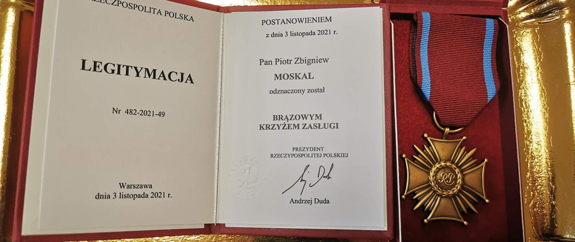 Zdjęcie przedstawia na złotej tacy położony w etui medal oraz legitymację