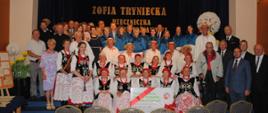 mężczyźni i kobiety w różnych strojach od eleganckich po ludowe i kolorowe pozują do wspólnego zdjęcia 