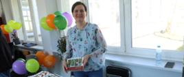 Prezentacja stoisk towarzyszących konferencji - pracownik Wydziału Promocji i Rozwoju Starostwa Powiatowego prezentuje foldery promujące turystykę w regionie