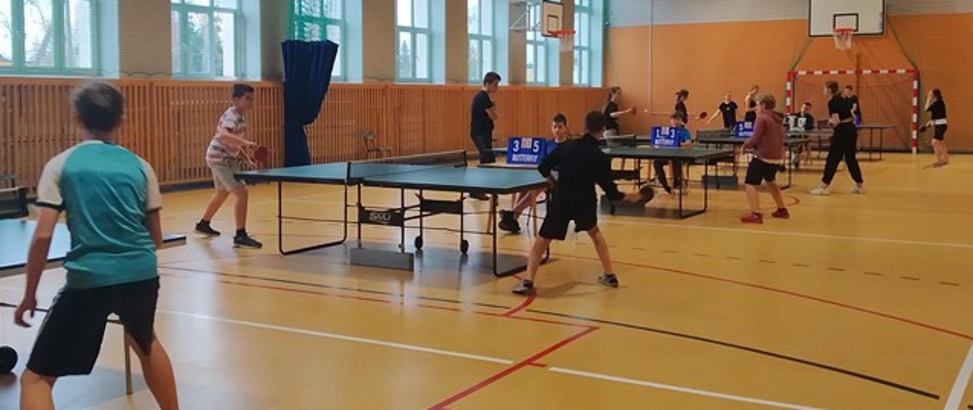 Uczestnicy w trakcie zawodów - rozgrywki przy stołach do tenisa