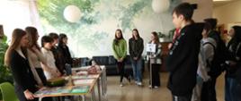 Szkolny korytarz - przy stoiskach edukacyjnych, przygotowanych przez uczniów szkoły stoją ósmoklasiści
