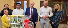 Grupa ludzi pozuje do zdjęcia w beżowej sali