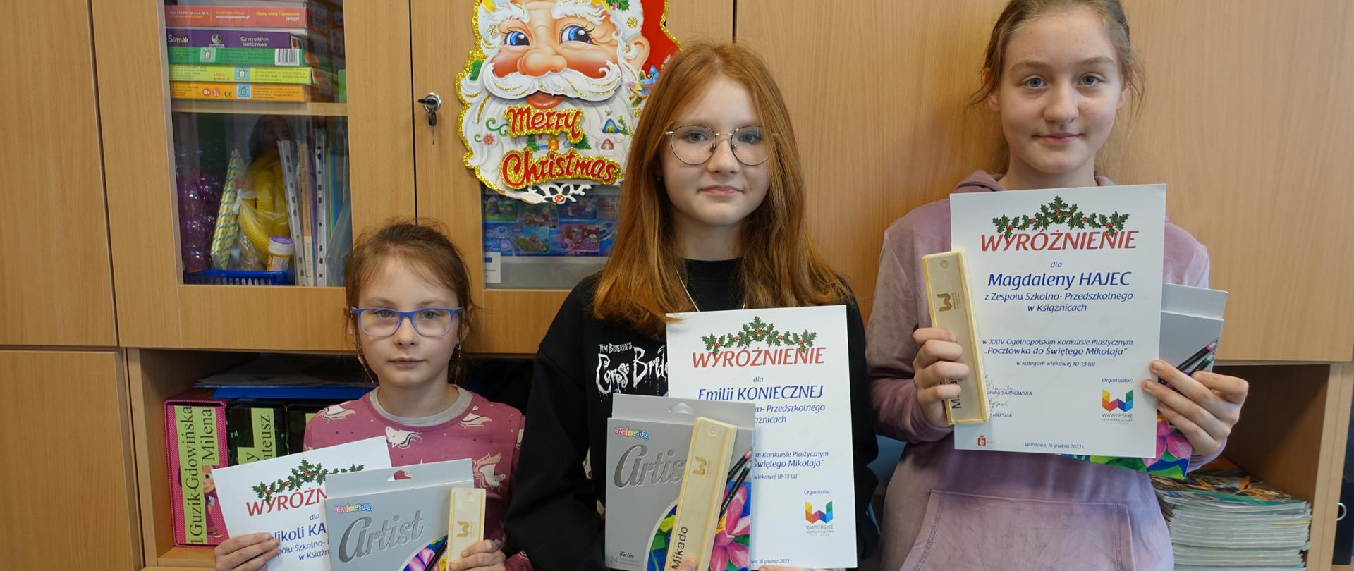 Trzy wyróżnione uczennice prezentują otrzymane dyplomy i nagrody.