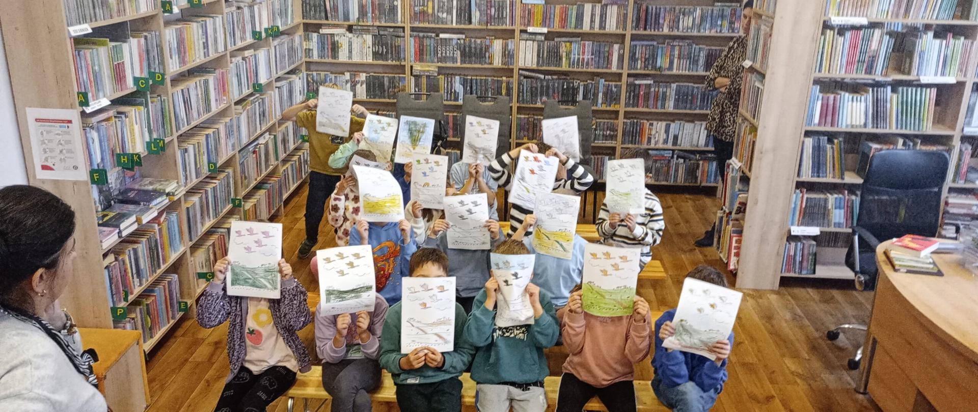 Na zdjęciu widzimy grupę dzieci, które prezentują pokolorowane obrazki