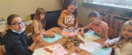 Pięć dziewczynek siedzi przy stole. Przed nimi obrazki baletnic a na środku stołu leżą kolorowe liście