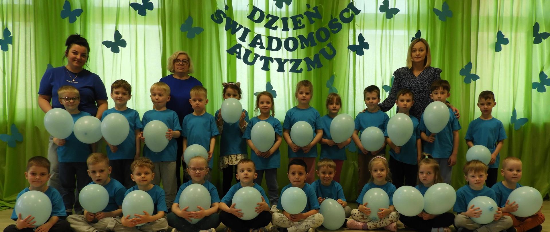 3 dorosłych i dzieci w niebieskich koszulkach i z balonami