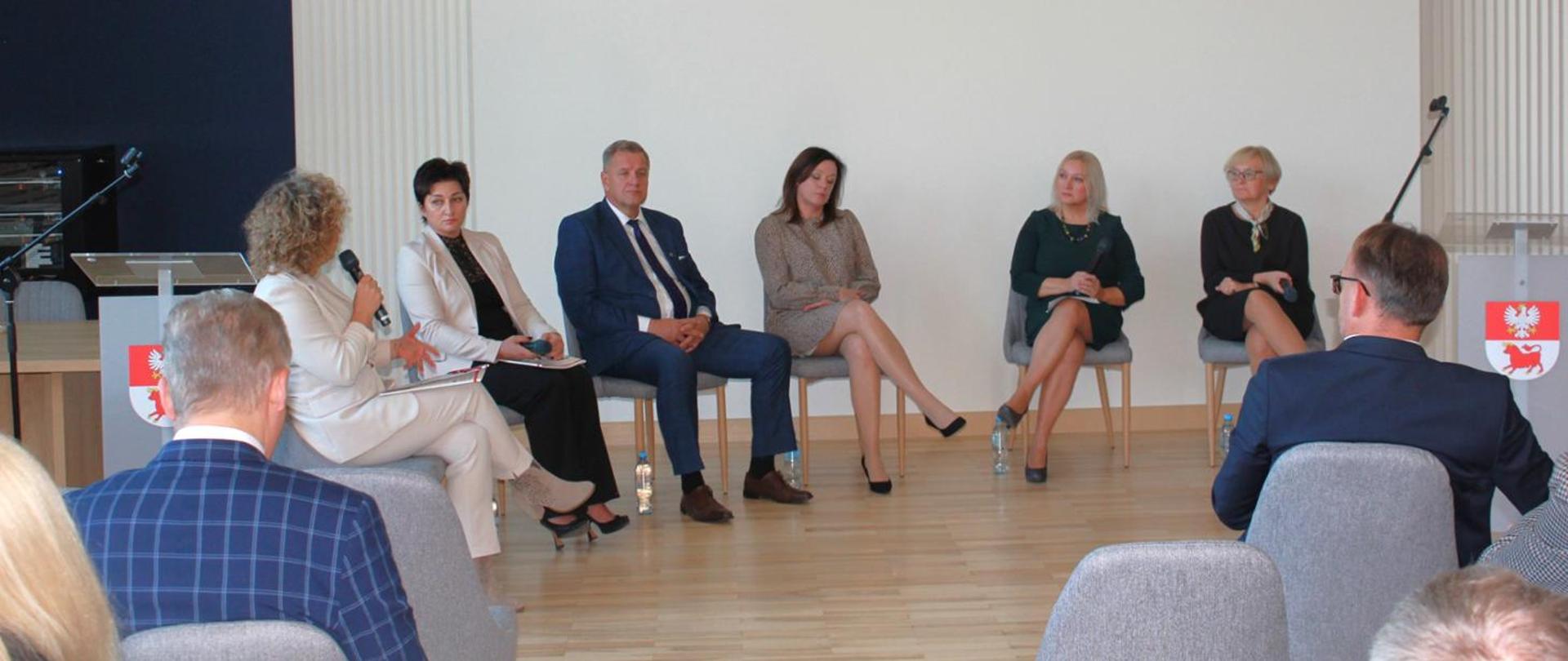 Uczestnicy panelu dyskusyjnego dyskusyjnego siedzą na krzesłach