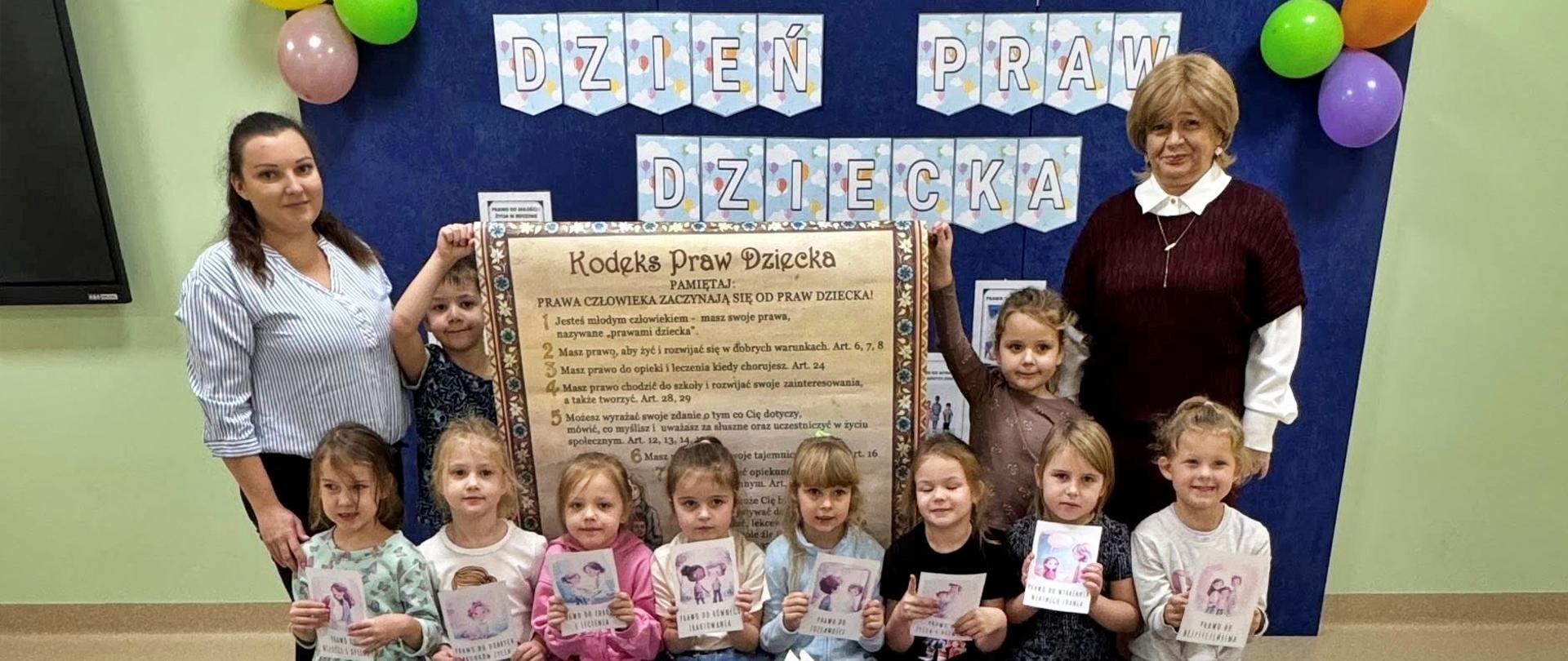 dzieci oraz opiekunowie przy planszy z prawami dziecka