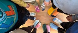 6 uczniów stoi w kole w różnych skarpetkach nie do pary - zdjęcie zrobione z góry, przedstawiające stopy ze skarpetkami