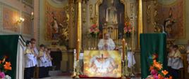 Ksiądz przy ołtarzu w czasie sprawowania eucharystii, po dwóch stronach widać ministrantów- uczniów szkoły.