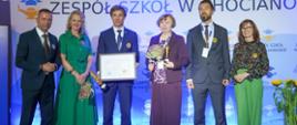 Osoby stoją na scenie z nagrodami