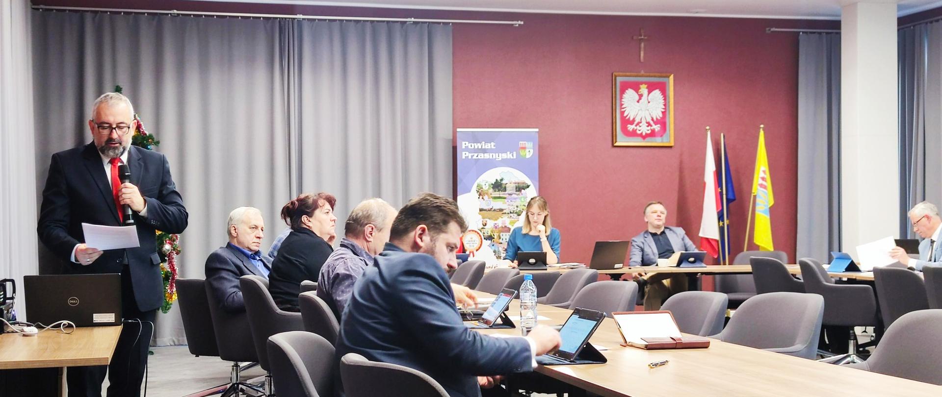 Zdjęcie przedstawia Starostę Przasnyskiego Krzysztofa Bieńkowskiego odczytującego radnym powiatu przedmowę do Strategii Powiatu Przasnyskiego, przyjętej podczas ostatniej sesji Rady Powiatu Przasnyskiego w roku 2022.