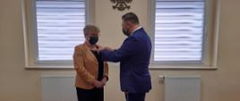 Wójt przypina medal pani Annie Hojce