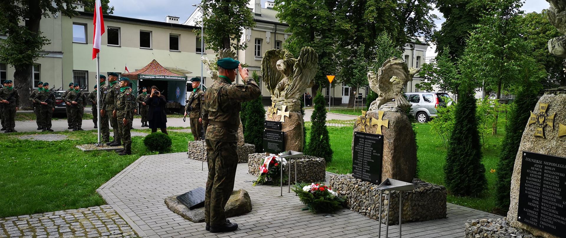 Obchody 82. rocznicy wybuchu drugiej Wojny Światowej w Przasnyszu. Fotografia przedstawia żołnierza salutującego przed pomnikiem poległych w obronie Ojczyzny.