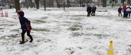 Zabawy na śniegu - dzieci na korcie pokonują tor przeszkód