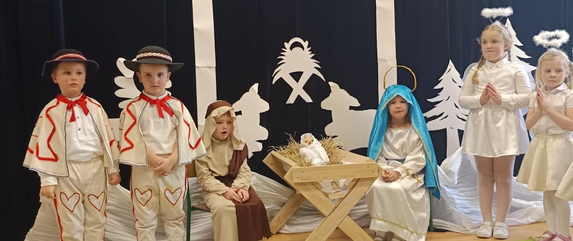 Dzieci występujące w jasełkach czuwają przy żłóbku 
