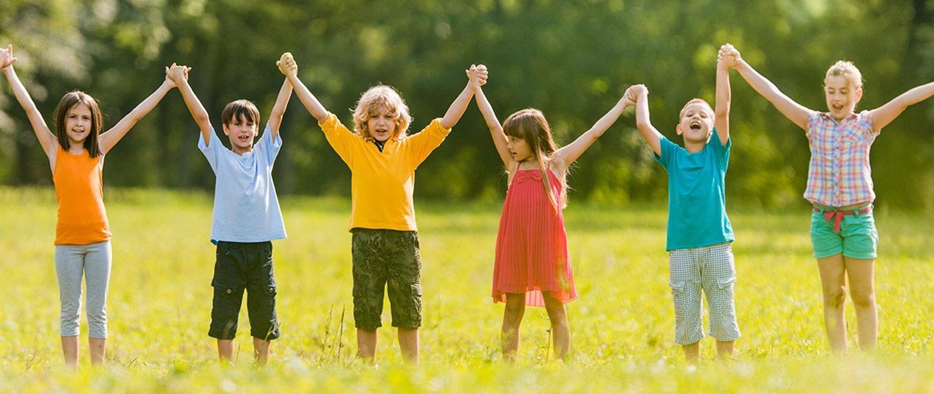 Large group of happy children holding hands in the park and having fun during spring day.