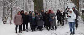Wspólne zdjęcie uczestników spaceru na tle zimowej puszczy