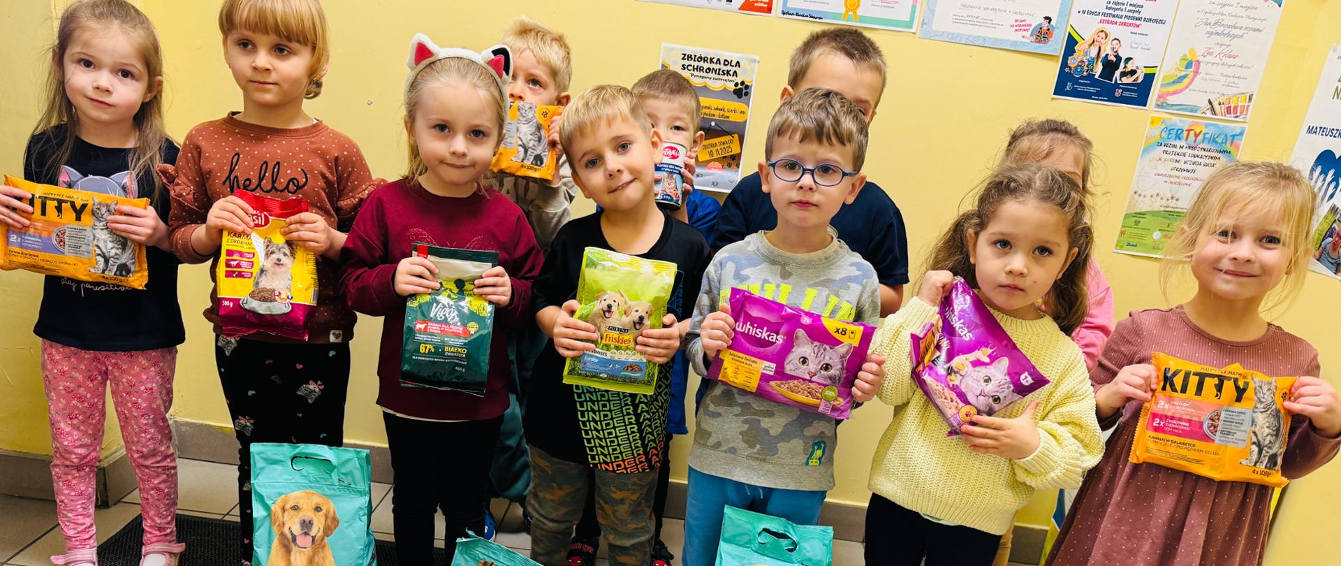 Dzieci pozują do zdjęcia z zebraną karmę w ramach akcji "Pomagamy zwierzętom"
