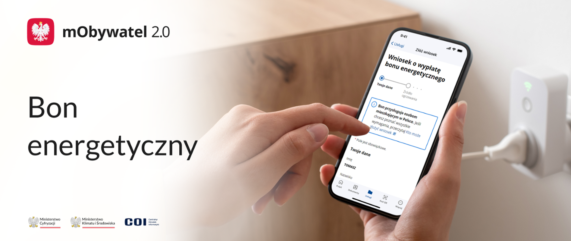 w lewym górnym rogu godło polski biały orzeł na czerwonym tle. Po środku dłonie trzymające telefon komórkowy