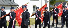 Na zdjęciu druhowie ubrani odświętnie, niosący sztandary