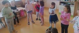 Przedszkolaki w swojej sali bawią się w kręgu w zabawę "Stary niedźwiedź mocno śpi", w tle tablica interaktywna z prezentacją związaną z misiem