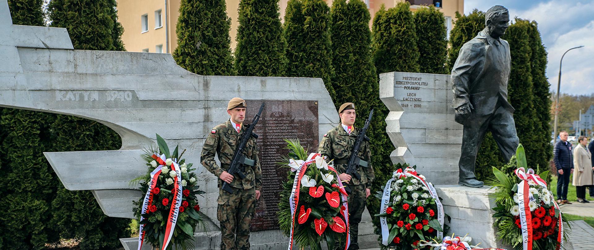 Zdjęcie przedstawia żołnierzy Wojsk Obrony Terytorialnej pełniących watrę przy przy Pomniku Prezydenta RP Lecha Kaczyńskiego oraz Ofiar katastrofy. Przed pomnikiem zostały złożone wieńce oraz znicze.