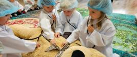 Grupa dzieci w fartuchach i czepkach medycznych podczas warsztatów medycznych
