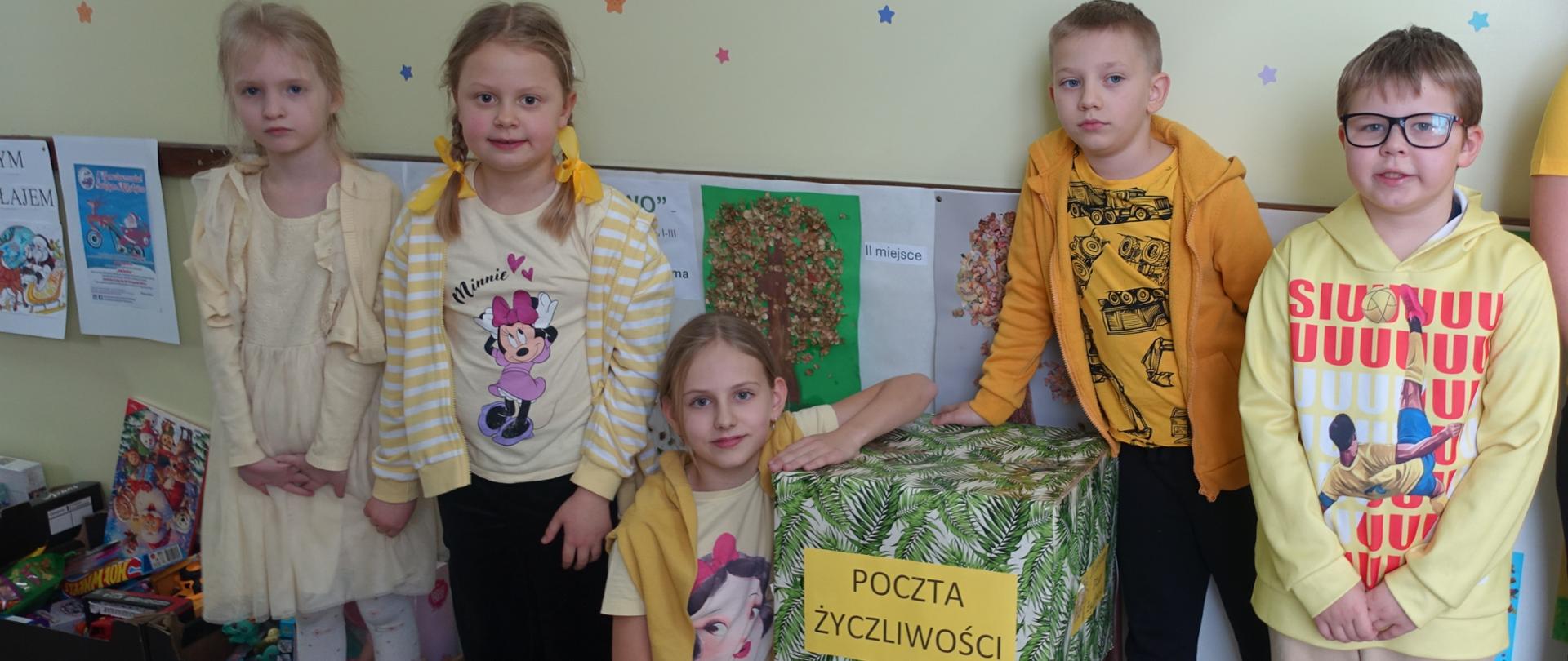 Uczniowie ubrani na żółto stoją przy Poczcie Życzliwości
