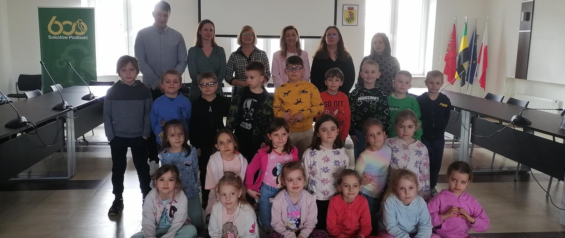 Grupa dzieci i dorośli na tle piramidy zdrowego odżywiania