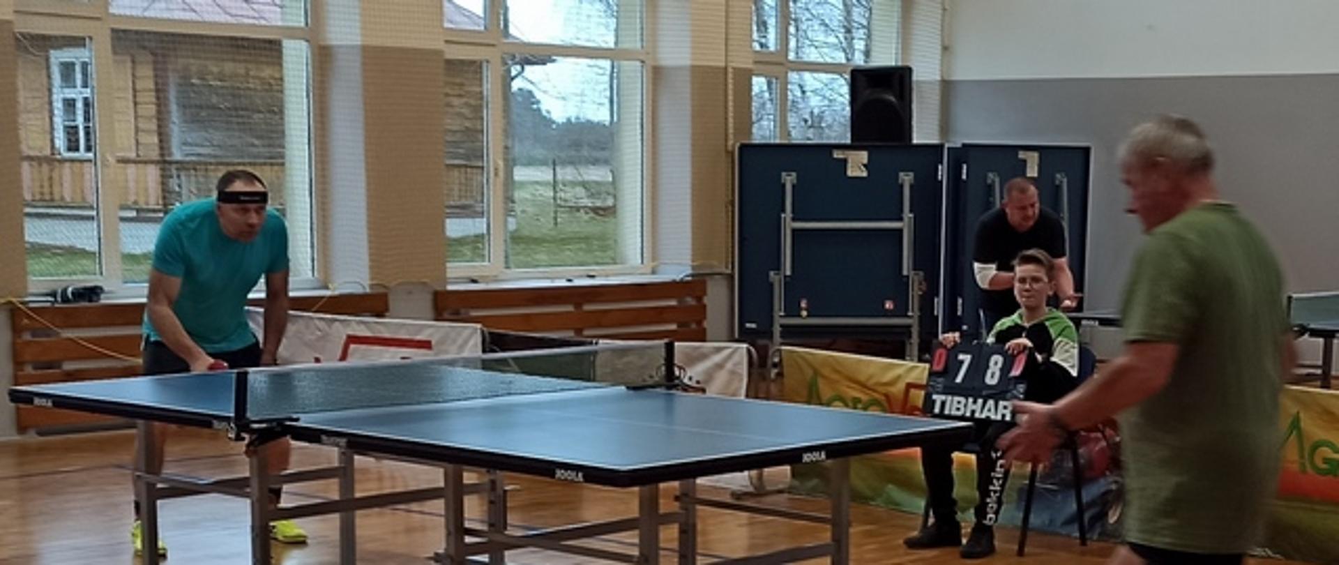 Dwóch uczestników przy stole tenisowym rozgrywa mecz