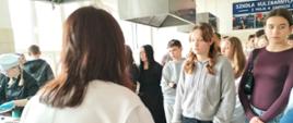 Uczniowie zwiedzają kuchnię w szkole średniej, po lewej widać uczennicę w stroju kucharza