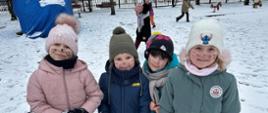 Dzieci pozują do zdjęcia, na twarzach mają namalowane kocie wąsiki
