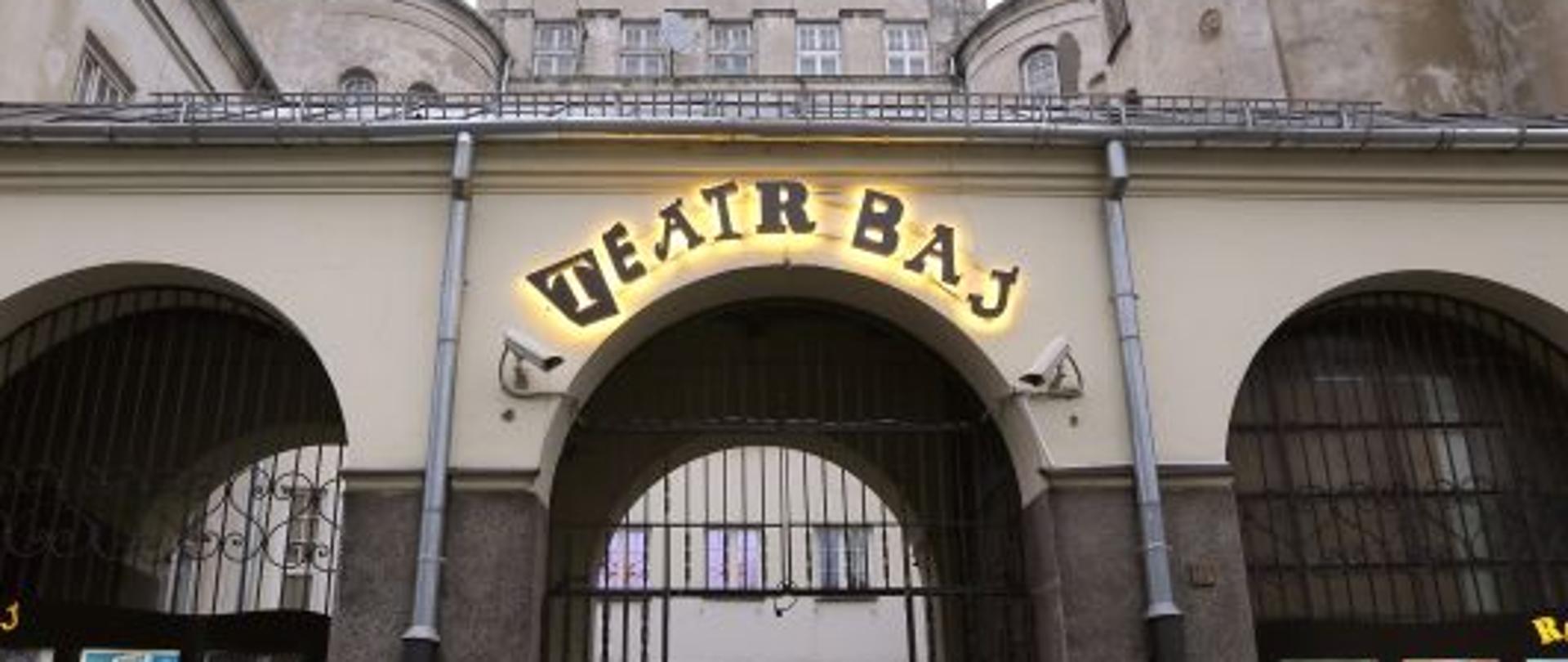 Otwarta brama z podświetlonym napisem Teatr Baj