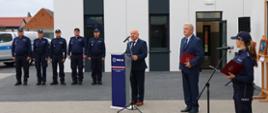 Burmistrz Miasta i Gminy Budzyń wraz z Zastępca przemawiają stojąc przed budynkiem nowego komisariatu 