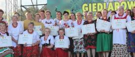 kobiety ubrane w stroje ludowe, stojące na scenie i pozujące do zdjęć 