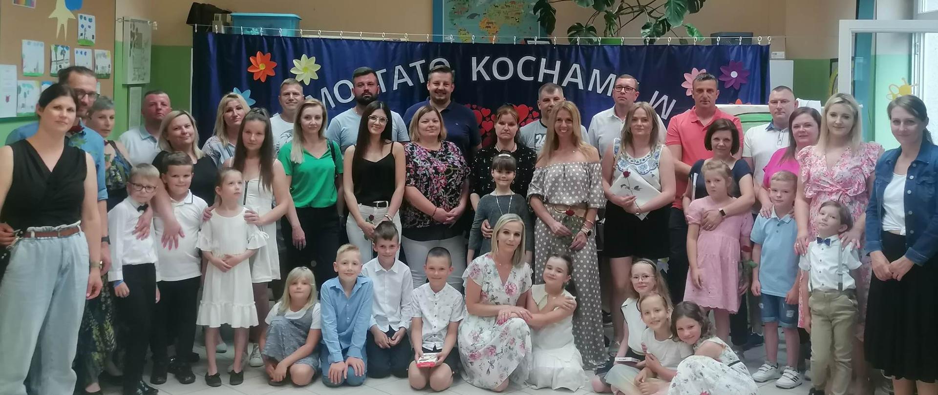 Grupa dorosłych i dzieci stojących obok siebie i kucających
