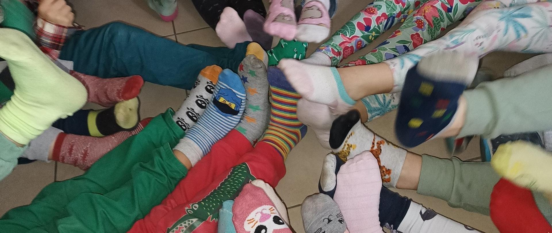 Dzieci siedzące w okręgu z kolorowymi skarpetkami nie do pary