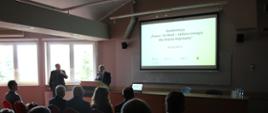 Prezentacja tematu konferencji - Starosta Hajnowski przy głosie, za nim ekran z prezentacją