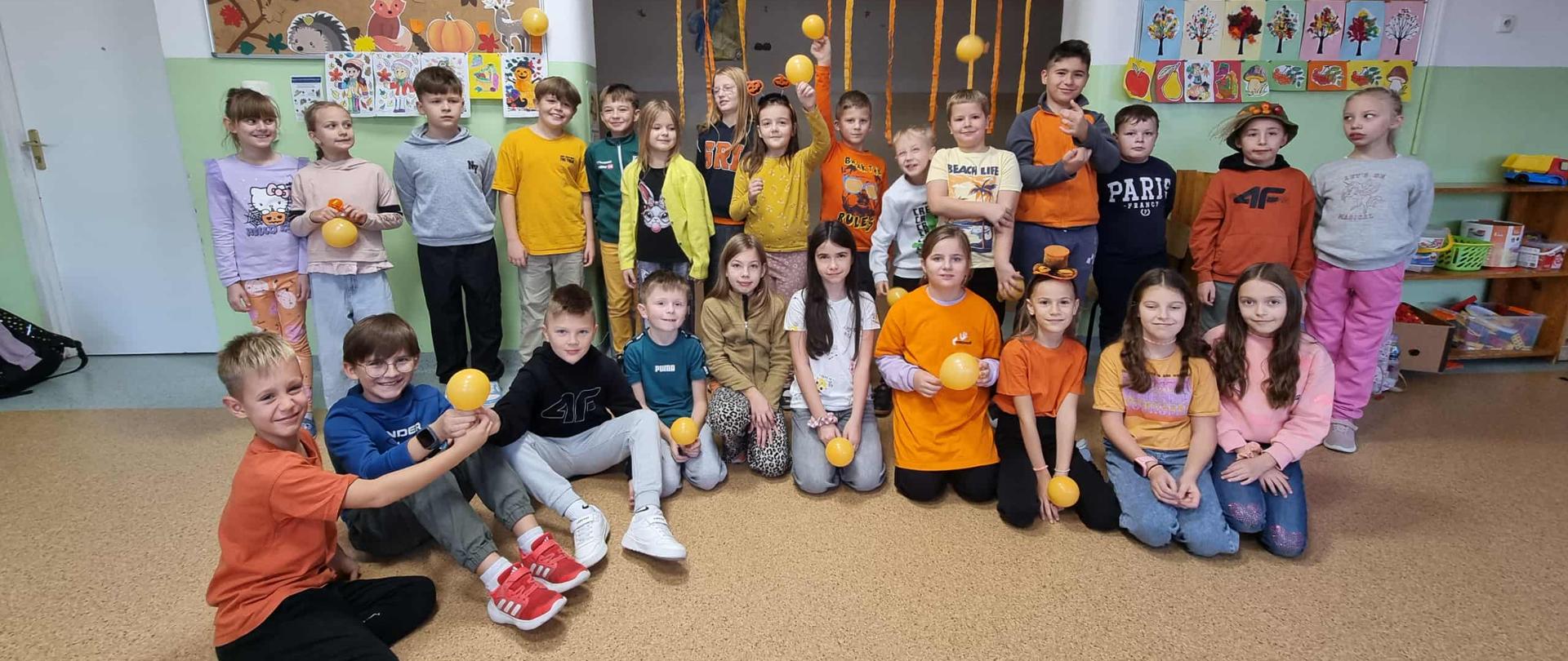 Grupa dzieci na świetlicy, pozująca na tle jesiennych dekoracji.