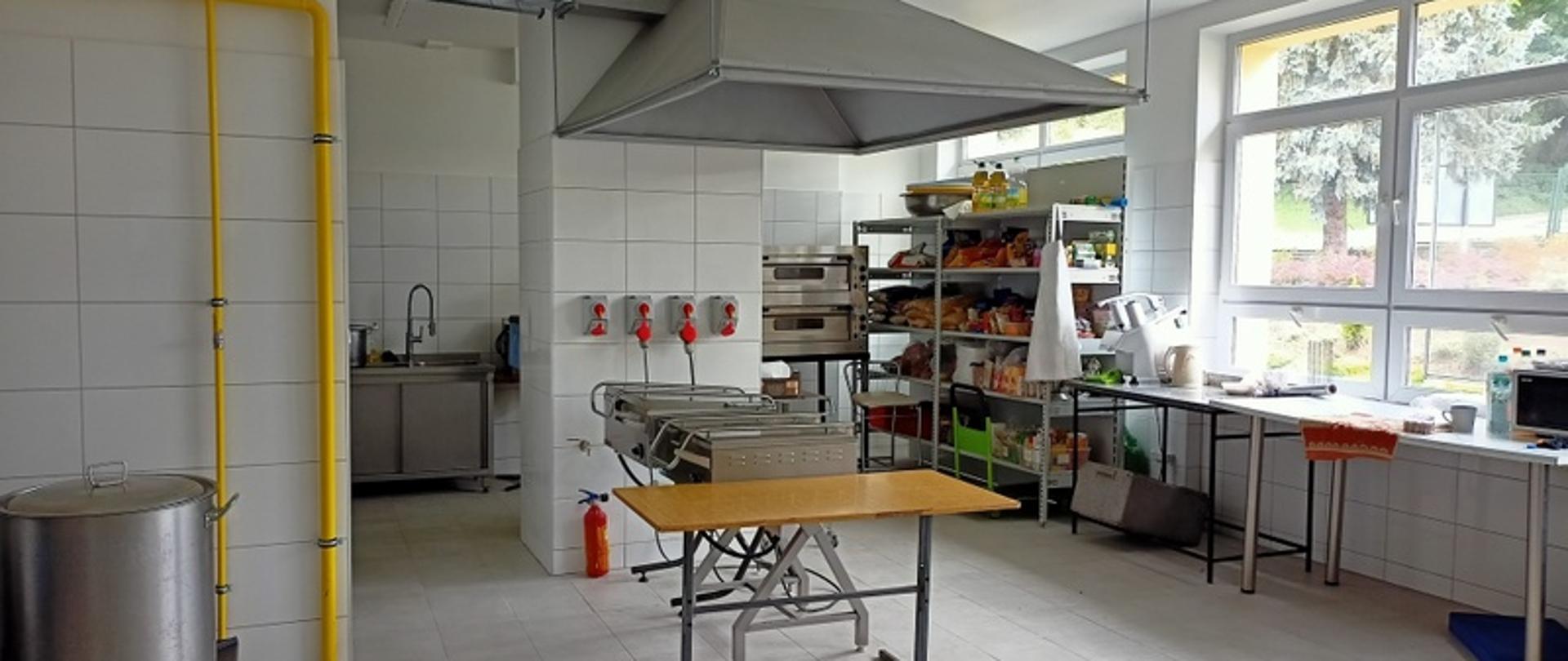 kuchnia po remoncie widoczne jasne płytki na ścianach i posadzce okap urządzenia kuchenne po prawej okna półki na produkty