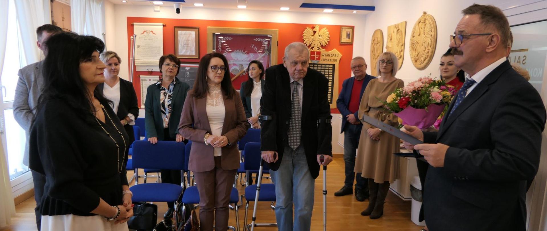 Starosta Lipski wręcza list gratulacyjny dyrektor lipskiego szpitala. W tle kierownicy i dyrektorzy, którzy podczas sesji otrzymali podziękowania.