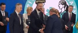 Na fotografii widzimy Ministra Obrony Narodowej, który ściska dłoń dyrektora SP ZOZ w Sokołowie Podlaskim podczas i wręcza mu teczkę z podpisanym porozumieniem.