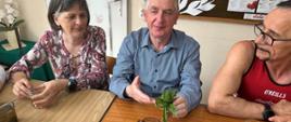 Uczestnicy warsztatów w trakcie zajęć - siedzą przy stole, poznają zioła